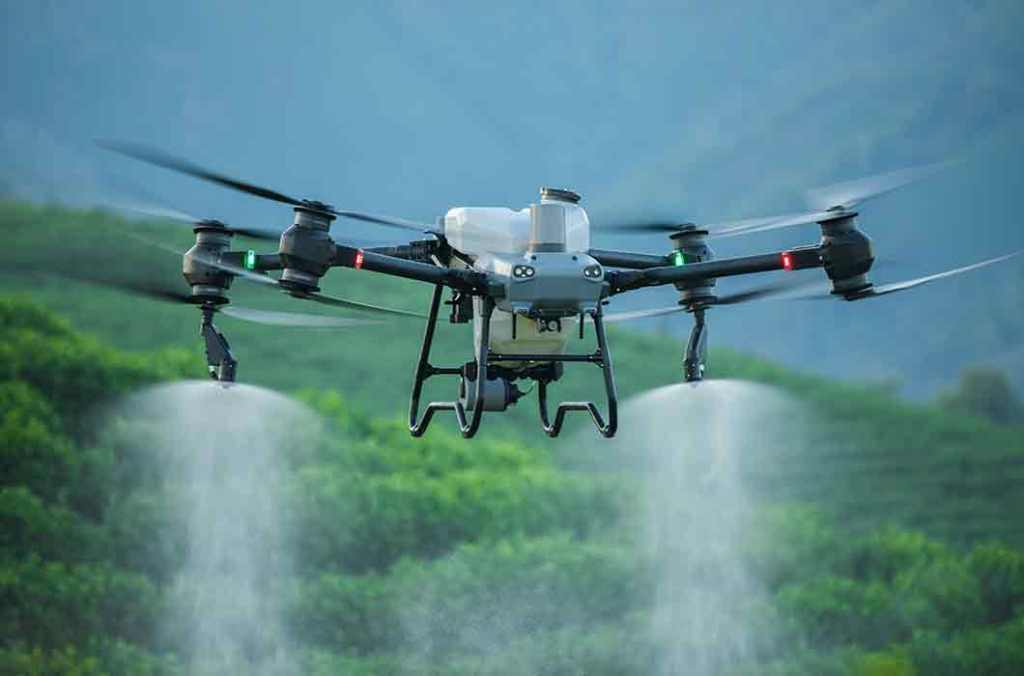 Drone agrícola en funcionamiento, aplicando productos sobre cultivos en un paisaje verde.